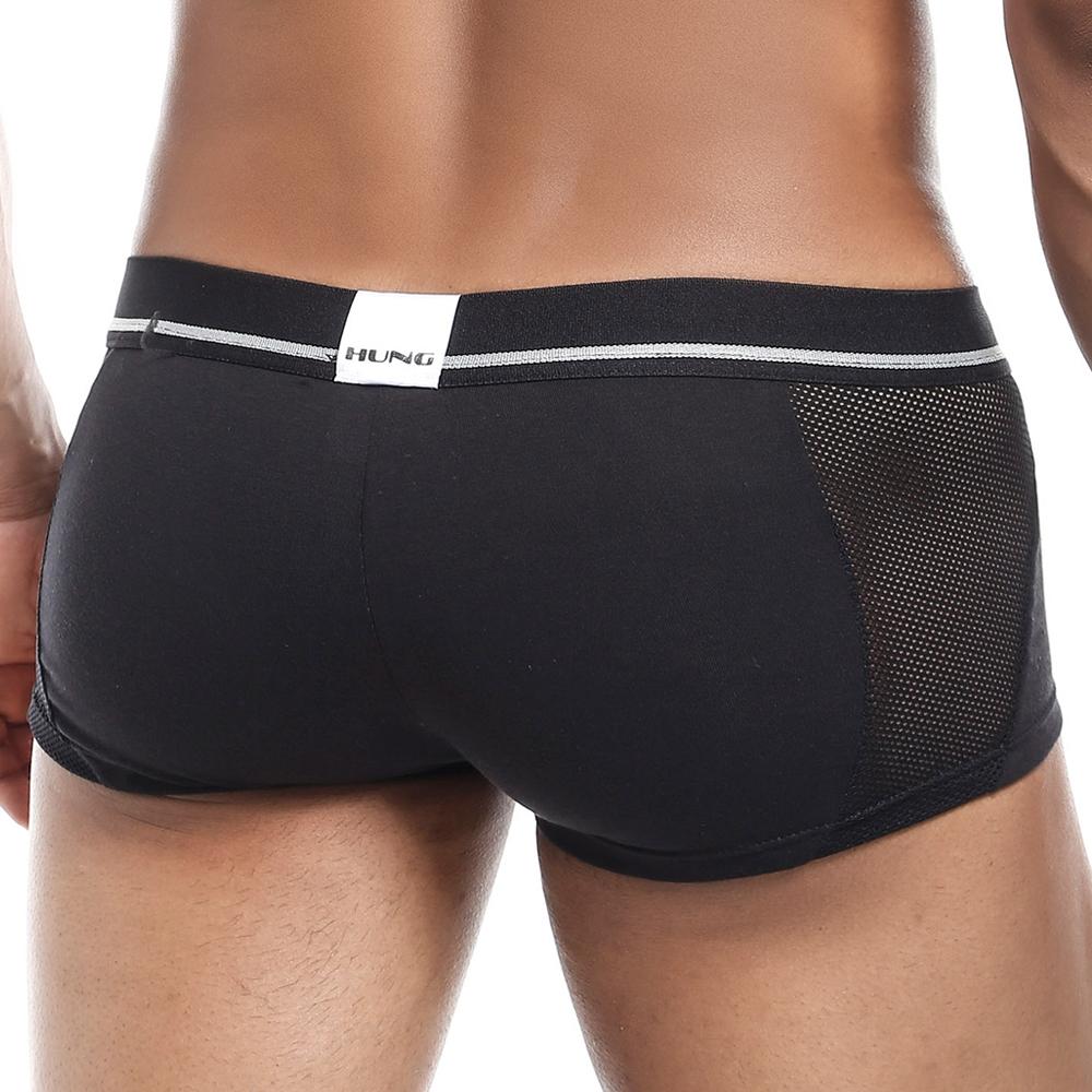 A person wears the Hung Clash Trunk, featuring black fitted underwear with a mesh side panel. The rear waistband displays the Hung brand name, highlighting a sleek Fabric Fusion design. The focus is on the Contour Pouch and lower back for optimal fit, comfort, and style.