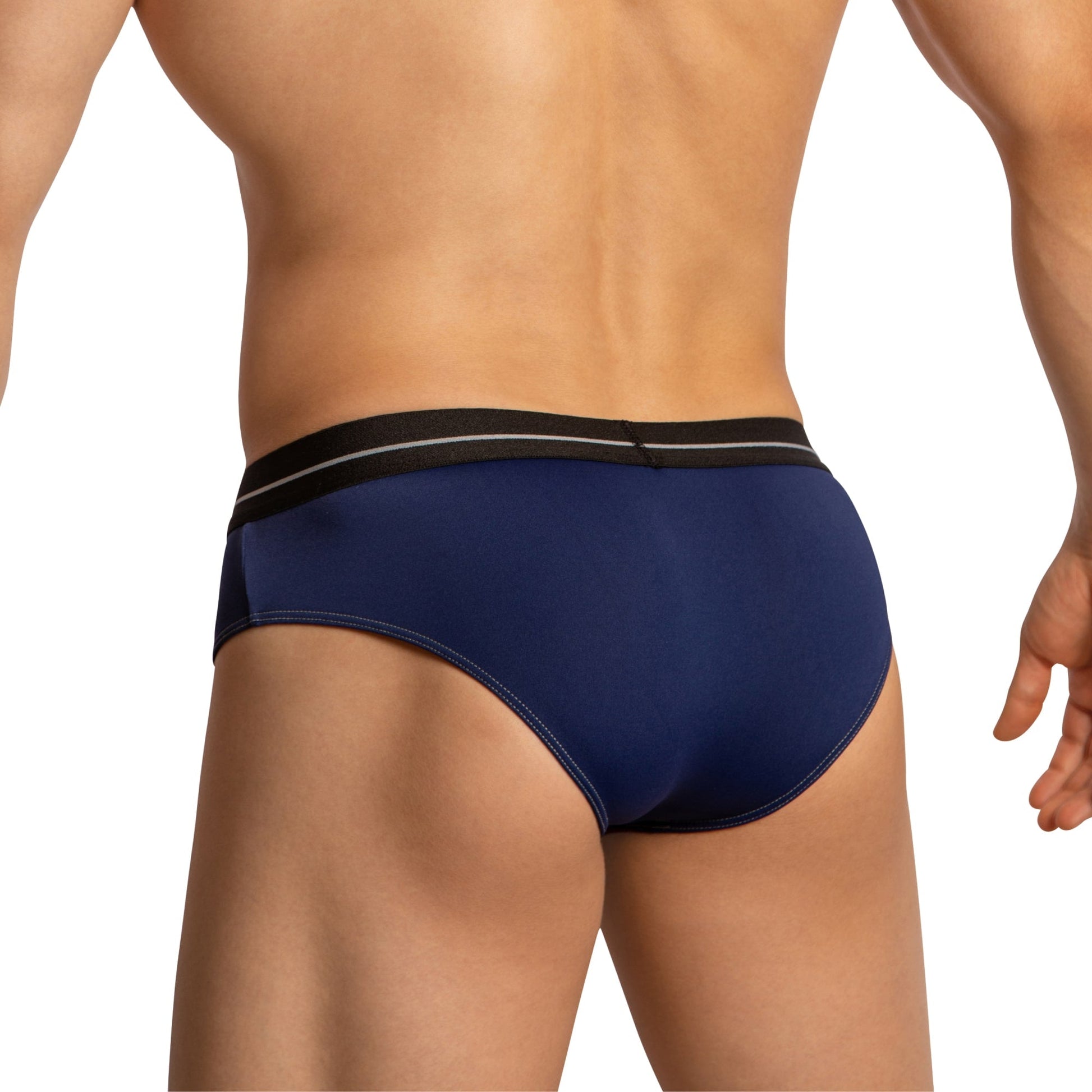 A person wearing Feel Thongs for Men, featuring a luxurious fabric blend and navy blue color with a black waistband, stands with their back to the camera.