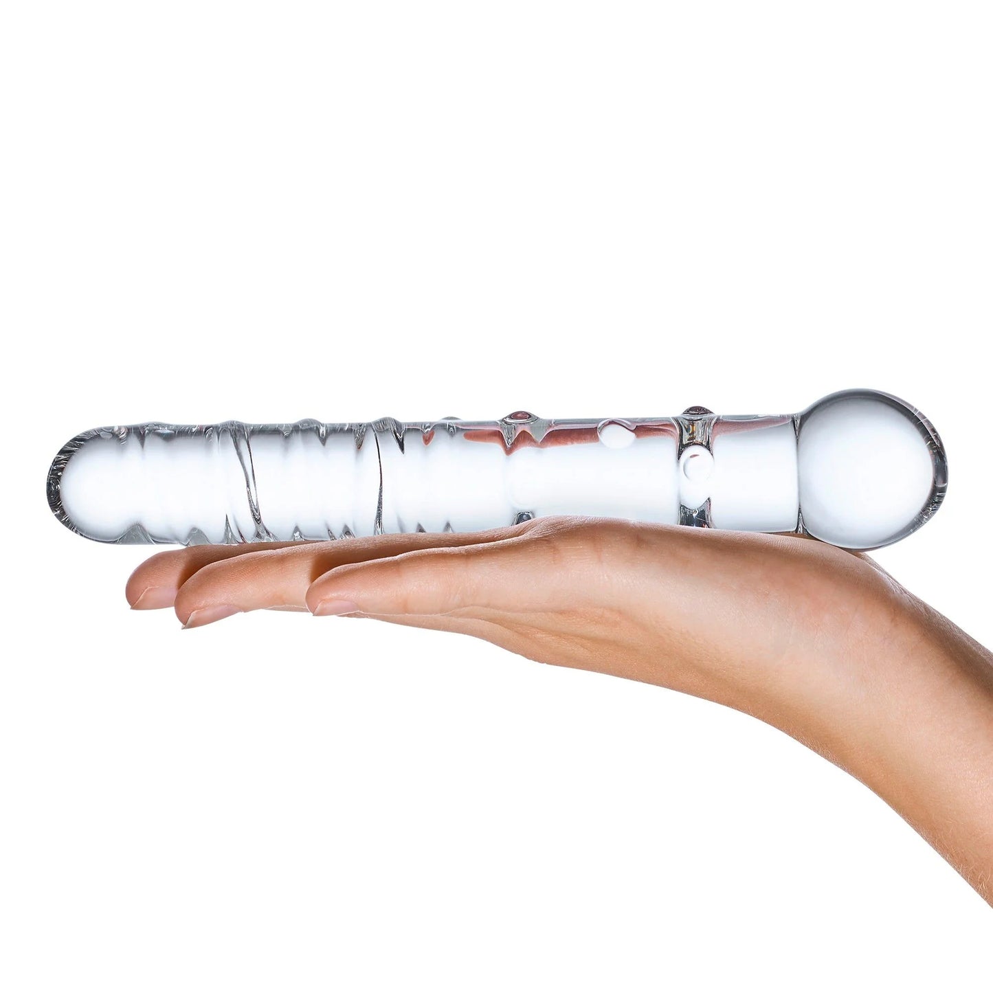 A hand elegantly cradles the Glas Callisto Glass Dildo by Glas, showcasing its artisan-crafted design with textured surfaces and rounded ends. This P-Spot pleasure tool is balanced horizontally on the palm against a plain white backdrop, highlighting its elegance and unique craftsmanship.