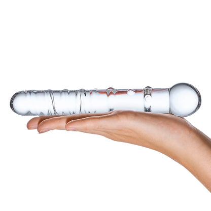 A hand elegantly cradles the Glas Callisto Glass Dildo by Glas, showcasing its artisan-crafted design with textured surfaces and rounded ends. This P-Spot pleasure tool is balanced horizontally on the palm against a plain white backdrop, highlighting its elegance and unique craftsmanship.