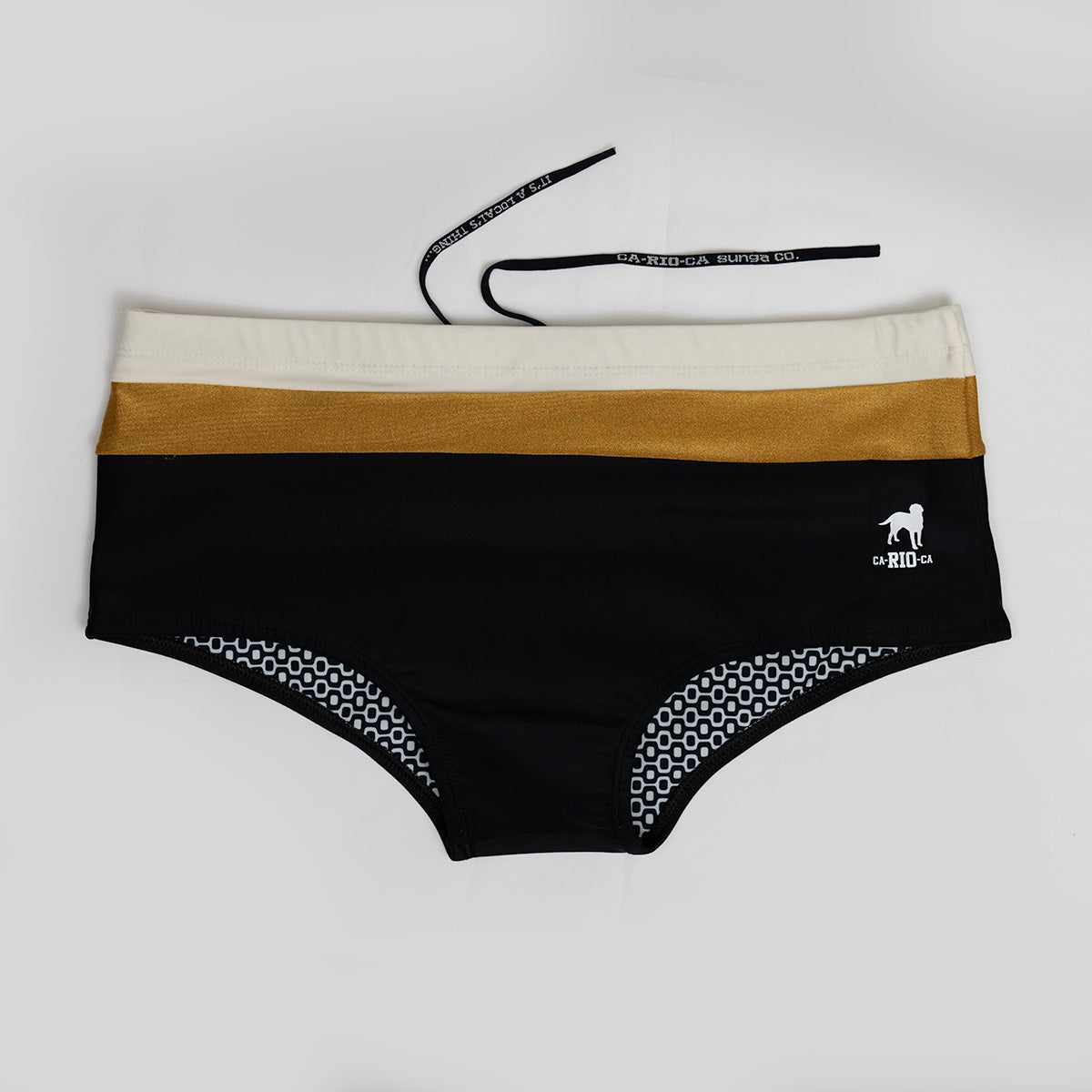 The Belmont Trio Sunga by CA-RIO-CA Sunga Co. is a high-waisted black bikini bottom with beige and gold bands, featuring a small white horse and rider logo. The interior boasts a custom black-and-white geometric print lining with an attached black drawstring.