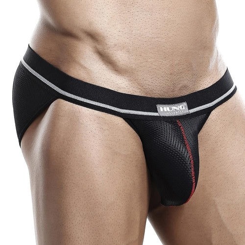 Someone wearing the Hung Jockstrap in black mesh with gray and red accents enjoys enhanced support. This breathable design ensures comfort, while a small logo on the waistband keeps attention on the clothing.