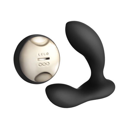 A black, ergonomically designed personal prostate massager sits next to a sleek round remote with metallic accents. The LELO HUGO remote features three buttons and a smooth finish, promising hands-free orgasms for an elevated experience.