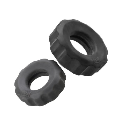 On a white background, two sleek Hunky Junk Cog Rings from the Cog Ring 2 Size Double Pack lie side by side, with the larger ring positioned to the upper right and the smaller to the lower left, both featuring black rubber foam grips.