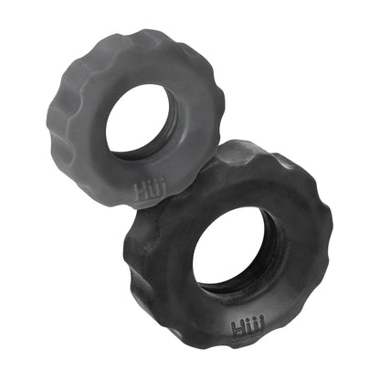 Two large, rugged black rubber dog toys resemble the Hunky Junk Cog Ring 2 Size Double Pack, made from a TPR/silicone blend with textured surfaces. Each features a central hole and Hüj embossed on the sides, positioned at an angle with one leaning against the other.